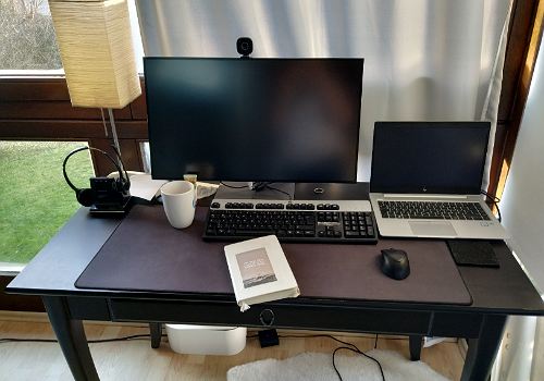 Schreibtisch mit Monitor, Notebook, Kaffeetasse und Notizbuch