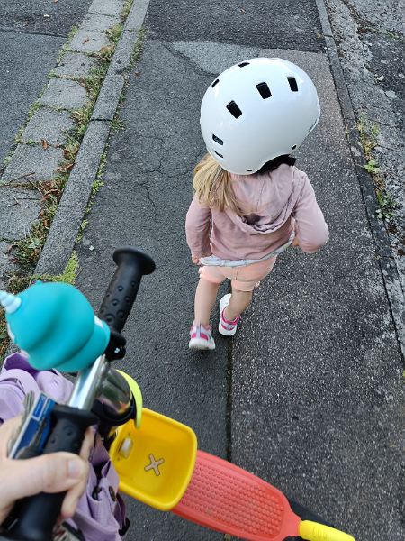 Kind mit Helm laufend auf dem Bürgersteig