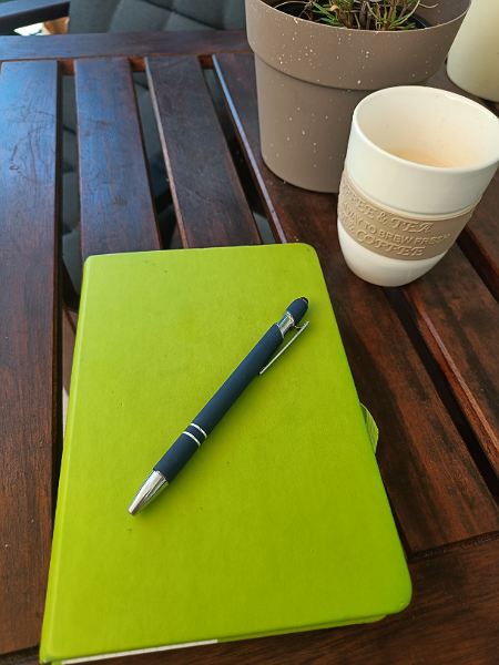 Notizbuch mit Stift und einer Tasse Kaffee