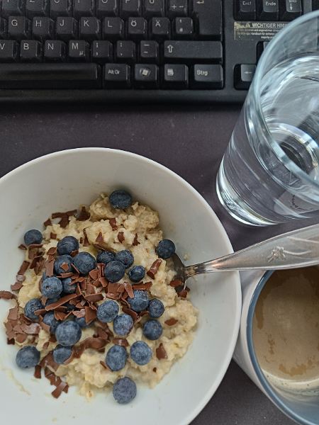 Porridge mit Blaubeeren und Schokolade, Kaffee und Wasser
